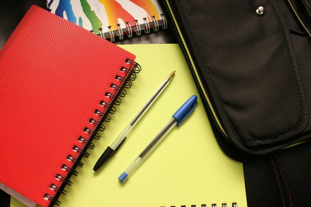Como posso ajudar o meu filho na escola? 5 Formas práticas para pais presentes black and blue pens beside red covered notebook