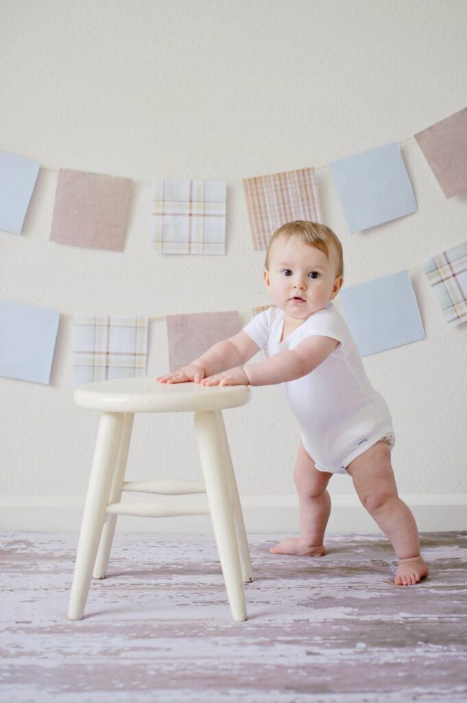 Desenvolvimento Infantil de 1 a 2 anos Imagem atual: baby holding white wooden stool