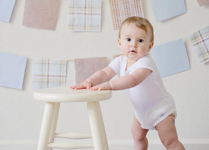baby holding white wooden stool